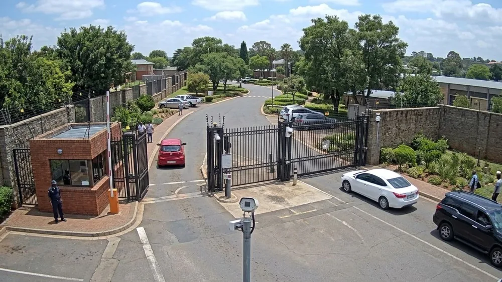 A gate camera: guard at the gatehouse, vehicles passing the barrier